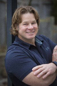 Photo of handsome Dave Boucher with his curly locks of hair and impressive bicep.